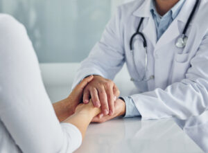 Holding patient by hands. professional medic in white coat is