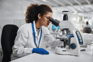 doctor in white lab coat using a microscope