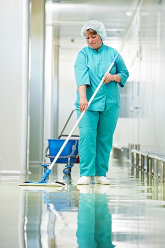 A woman sanitizes the floor of a medical facility